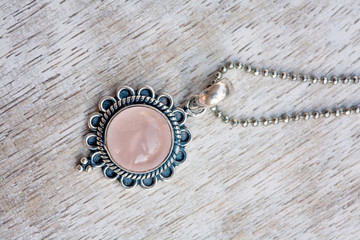 Silver pendant on neutral bright wooden background