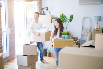 Young beautiful couple moving cardboard boxes at new home