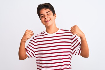 Handsome teenager boy standing over white isolated background very happy and excited doing winner gesture with arms raised, smiling and screaming for success. Celebration concept.