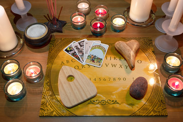 Fototapeta na wymiar Ouija-Brett mit brennenden Kerzen, entzündeten Räucherstövchen und Räucherstäbchen
