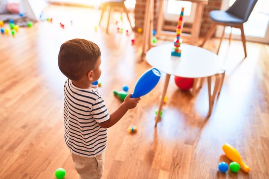 Beautiful toddler boy playing bowling at kindergarten
