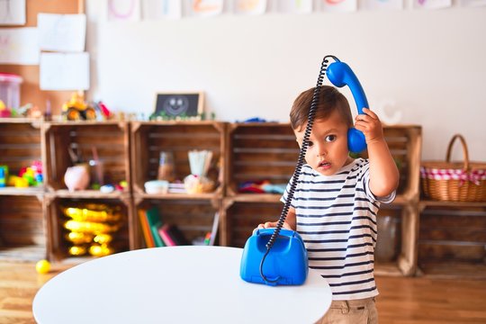 Beautiful toddler boy playing with vintage blue phone at kindergarten