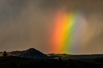 Wide Rainbow Glows Through Thick Storm Cloud