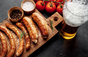 Different grilled sausages with beer with spices on a stone table with copy space for your text