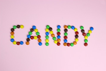 The word candy are contained by colored candies on a pink background