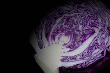 Red cabbage sliced in half isolated on a black background.  With lighting effect.