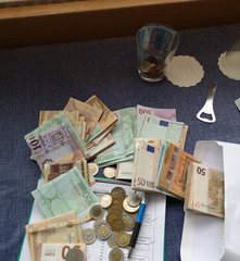 Hungarian Forint and Euro coins and paper banknotes on a table with a glass and a pen