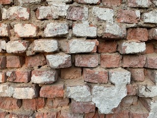 Background texture: old, damaged red brick wall. Shabby building facade with damaged stucco.