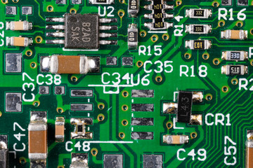 green card computer board with brown microcircuits and various electronic components, top view,...