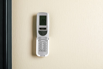 Air conditioner remote control on white concrete wall.