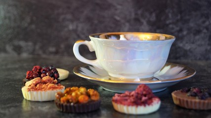 chocolate candies decorated with berries on a background of a white porcelain cup