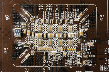 black computer video card board with brown microcircuits and various electronic components, top...