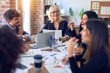 Group of business workers smiling happy and confident. Working together with smile on face  using laptop and speaking at the office