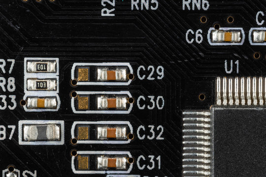 black computer video card board with brown microcircuits and various electronic components, top view, macro photo