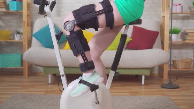 young woman knee bend orthosis knee brace after injury on a stationary bike knee bend orthosis knee brace after injury