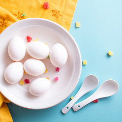 Festive Easter colored background with white eggs with sweets . flat lay with copy space. Compositions in trendy colors. 