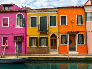 Fototapeta na wymiar The colorful, brightly painted houses on the Venetian island of Burano. A boat is moored on the canal - Burano, Venice - Italy