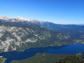 A beautiful view from above of Lake Bohinj and the Bohinj valley with the mountains in the background