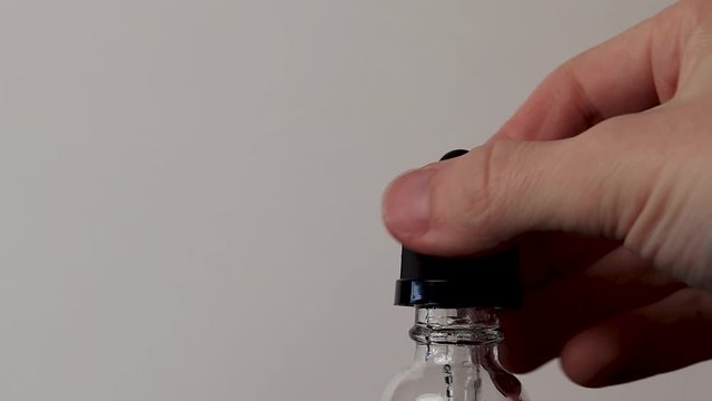 Unscrewing the top of a cbd dropper bottle before carefully measuring out the cbd thc oil to be administered medicinal marijuana tincture. 
