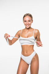 Young woman measuring her body with a tape and looking in camera . Healthy lifestyles concept