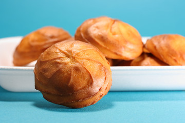Golden cookies in a white plate on a turquoise background