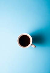 Cup of hot fresh black coffee on blue background