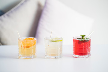 Three colourful cold drinks on a row, flavour orange, lime and red berries.