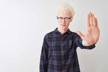 Young albino blond man wearing casual shirt and glasses over isolated white background doing stop sing with palm of the hand. Warning expression with negative and serious gesture on the face.