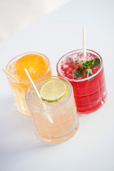 Three fresh colourful drinks lime orange and red fruits topview