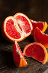 Slices of ripe fresh organic grapefruit on a rustic wooden board. Natural source of vitamins, low calories tasty dessert. Dark background, close up, front view