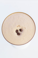 cold foamy coffee drink  overhead view , decorated with coffee beans. bright background