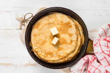 Crepes in the frying pan on white table.