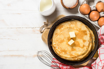 Crepes or thin pancakes in the frying pan with ingredients for cooking.