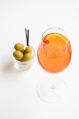 Spritz apero beverage and green olives on bright surface, topview shallow focus