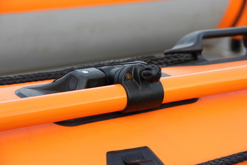 Close up rowlocks and oar orange PVC inflatable boat tube