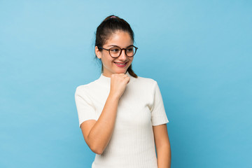 Young brunette girl over isolated blue background with glasses