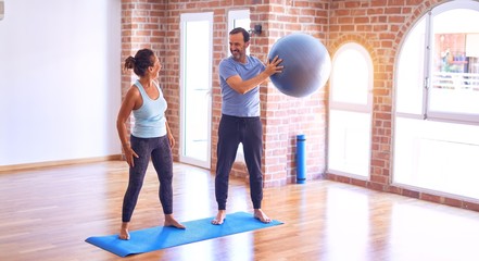 Middle age beautiful sporty couple smiling happy. Standing with smile on face highing five at gym