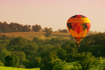 A hot air balloon floats above an Iowa rural landscape. - obrazy, fototapety, plakaty