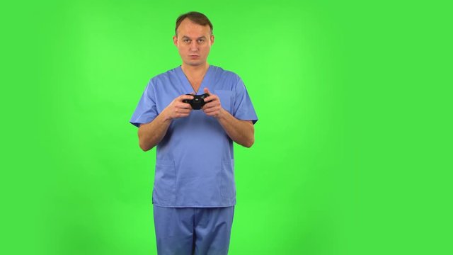 Medical man playing a video game using wireless controller and rejoicing in victory. Green screen