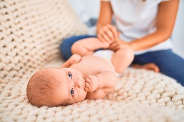 Young beautifull woman and her baby on the sofa over blanket at home. Newborn and mother relaxing and resting comfortable