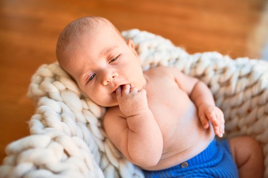 Adorable baby lying down on the floor over blanket at home. Newborn relaxing and resting comfortable