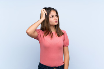 Young brunette girl over isolated blue background having doubts and with confuse face expression