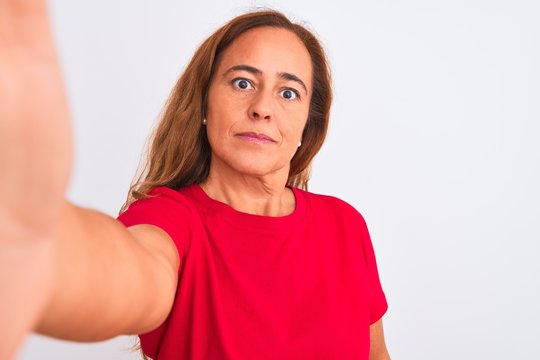 Middle age mature woman taking a selfie photo using smartphone over isolated background with a confident expression on smart face thinking serious