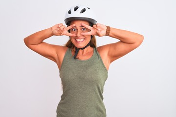 Middle age mature cyclist woman wearing safety helmet over isolated background Doing peace symbol with fingers over face, smiling cheerful showing victory