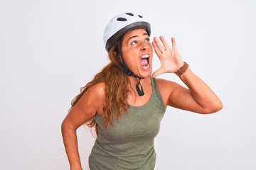 Middle age mature cyclist woman wearing safety helmet over isolated background shouting and screaming loud to side with hand on mouth. Communication concept.