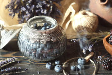 blueberries and blackberries in a vintage jar and wooden plate, lavender and dried flowers. vintage village style