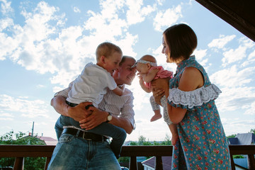 Mom and Dad, with young children in their arms have fun like crazy against the clouds