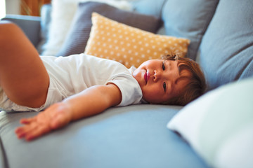 Beautiful toddler child girl wearing white bodysuit lying down on the sofa