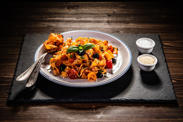 Tagliatelle with sausages and vegetables on wooden table