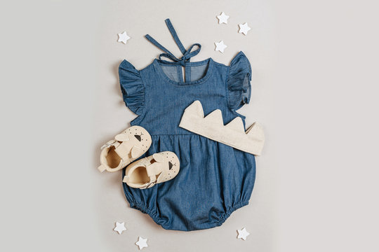 Blue romper with cotton crown and baby shoes. Cute set of baby clothes and accessories for girl. Fashion newborn bodysuit. Flat lay, top view